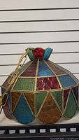 Photo showing the stained glass ceiling light fixture with multicolored textured glass panels framed in brass-colored metal.