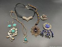 Full lot showing all necklaces and earrings on a black surface