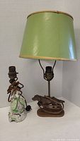 Full image of both lamps side by side, showing the China lady lamp on left and metal dog lamp on right with green shade.