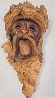 Front view of the detailed wood carving showing the bearded face with textured mustache and expressive mouth.