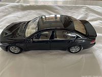 Side profile photo of glossy black BMW 745i diecast model, showing smooth finish, proportionate details, and wheels.