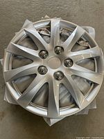 Top view of a 14-inch silver multi-spoke universal wheel cover showing chrome lug nut cover details and center cap area.