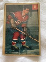Front side of 1954-55 Parkhurst hockey card #11 showing a player in red and blue uniform holding a stick, with visible wear and creases.