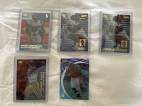 Five football cards in protective sleeves, including Dennis Northcutt, Tory Holt, Jamal Anderson, and Warrick Dunn.