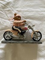 Side view of Faithful Fuzzies bear figurine on pink and silver motorcycle on gray base showing details of bear outfit and bike components.