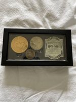 Closed view of black display case holding 3 coins and an information card.