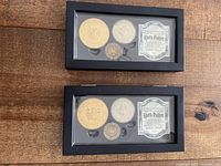 Lot showing two closed black display cases, each holding Harry Potter collectible coins and certificates inside.