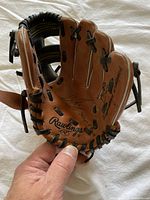 Top view photo showing brown leather baseball glove with black lacing and Rawlings logo and signature on palm