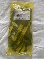 Sealed yellow plastic bag containing tool tether attachments, with visible yellow straps and metal cinch parts.