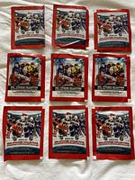 Nine unopened NHL Topps sticker packs arranged in two rows with 2022-23 and 2023-24 collections against a neutral background.