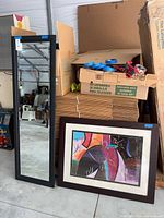 Mirror and framed abstract art leaning against stack of boxes