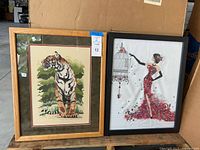 Both framed cross-stitch artworks side by side showing subjects, frames, and overall condition