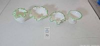 Full group of four milk glass pieces with green ruffled rims