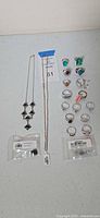 Full lot overview showing two necklaces, twelve rings, two sealed earring pouches