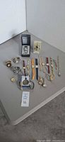 Tabletop view of entire lot: wristwatches, pocket watches, presentation box, display case