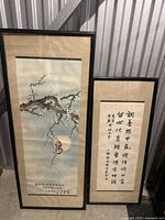 Framed art of blossoming branch with bird and adjacent framed calligraphy text
