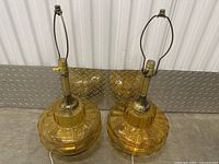 Pair of amber glass Art Deco style lamps with brass fittings and harps, on concrete floor