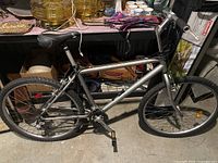 Side view of a silver mountain bike with black seat and tires, displayed indoors