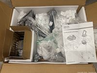 Overall view of all components of the BIOS medical monitor stand, parts wrapped in plastic inside shipping box.