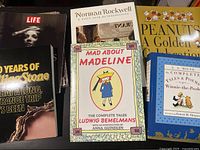 Six books arranged, showing cover titles including Norman Rockwell retrospective, Madeline tales, Life magazine, and 50 Years of Rolling Stone.