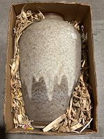 Top-down photo of the vase in packing box with shredded paper.