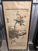 Full view of framed Asian floral artwork depicting a cherry branch with leaves and fruits, with calligraphy and red stamps in the upper right and bottom area.