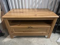 Front view of wooden Ikea table with drawer and metal handle, showing natural wood grain and rectangular shape.