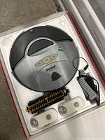 iRobot Roomba vacuum cleaner in its styrofoam packaging with included charger and brushes
