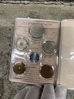 Set of six Japanese coins fixed in a transparent display case with detailed background info visible.