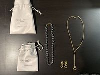 Full lot with necklaces, earrings, and jewelry pouches displayed on a dark surface