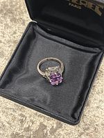 Close-up photo of the vintage silver ring with a purple gemstone in a black velvet case