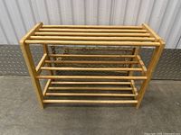 Photo of a wooden shoe rack with three tiers constructed from cylindrical rods in a light natural wood finish.