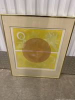 Framed abstract art print with a gold-colored frame and a yellow background featuring a large brown circle and white shapes.