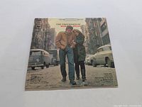 Front cover of The Freewheelin' Bob Dylan album showing Bob Dylan and a woman walking on a street.