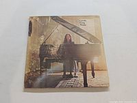 Front cover of Carole King Music LP showing Carole King seated at a grand piano.