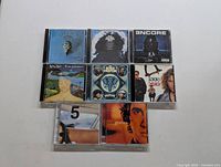 Top-down photo showing 8 miscellaneous music CDs arranged in two rows on white background. Album covers visible for identification.