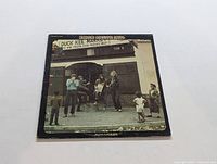 Front cover of the Creedence Clearwater Revival LP Willie and the Poor Boys showing the band in front of Duck Kee Market.