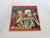 Front cover of the Grateful Dead album 'The Best of Skeletons From The Closet' showing artwork featuring a skeleton with a cymbal and two other figures.
