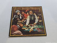Front cover of Kenny Rogers LP The Gambler showing artwork of several people playing cards around a table.