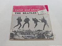 Front view of The Beatles Twist and Shout LP album cover showing the band jumping in black and white with red and white title band.