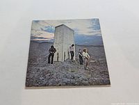 Front cover of The Who LP "Who's Next" showing band standing near a concrete monolith on rocky ground beneath a cloudy sky.
