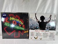 Front covers of two sealed vinyl records: Red Hot Chili Peppers Unlimited Love with neon sign style art and Playboi Carti Die Lit back cover showing crowd and tracklist.