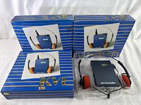 Three vintage KVI 570 AM/FM portable radios in original blue and gold striped boxes with the original sealed foam headphones included.