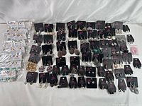 Full display of over 70 pairs of earrings on branded cards from Paparazzi and Glitter & Grace, showing mixed metal finishes and variety of styles.