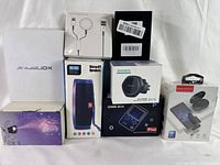 Photo displays all 8 boxed electronic devices including wireless mic, game console, chargers, speaker, projector, and mystery box arranged on a white surface.