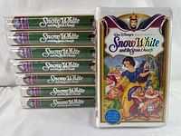 Lot of eight factory-sealed VHS tapes stacked horizontally with the original shrink wrap intact, showing the green spine labels.