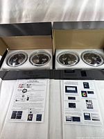 Two sets of Jeep RGB color-changing headlights in black boxes with foam packing, showing the front of the headlights with clear lenses and multiple LED light elements inside, alongside instruction sheets.