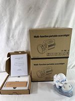 Opened box showing multi-function portable searchlight packaging and astronaut night light figurine on base.