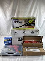 Photo showing the boxed PowerEvolv cordless leaf blower, Minoxidil topical treatment box, and multiple other boxed items including the RV fan housing and a large white box possibly containing the solar-edge device.