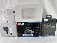 Five electronic devices: white aroma diffuser, Black Box traffic recorder in box, Ultrapods wireless earbuds in package, clip-on phone light, charging cable
